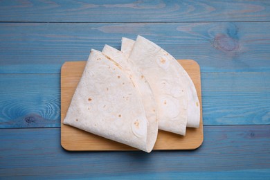 Photo of Delicious folded Armenian lavash on light blue wooden table, top view