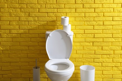 Simple bathroom interior with toilet bowl near yellow brick wall indoors. Home design