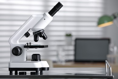 Photo of Modern medical microscope on metal table in laboratory, space for text