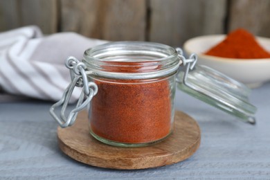 Photo of Jar with aromatic paprika powder on grey wooden table