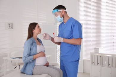 Doctor taking nasal smear of pregnant woman for coronavirus test in clinic