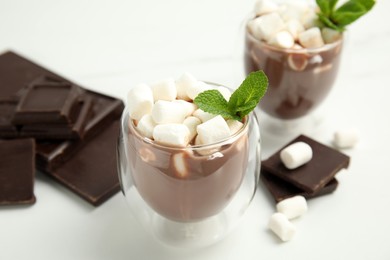 Glasses of delicious hot chocolate with marshmallows and fresh mint on white table
