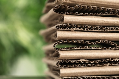 Stack of cardboard for recycling on blurred background, closeup. Space for text