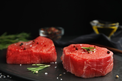 Fresh raw beef cut with spices on black table, closeup