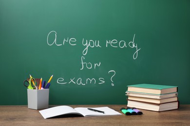 Different stationery and books on wooden table near chalkboard with phrase Are You Ready For Exams