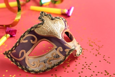 Beautiful carnival mask with party decor on coral background, closeup