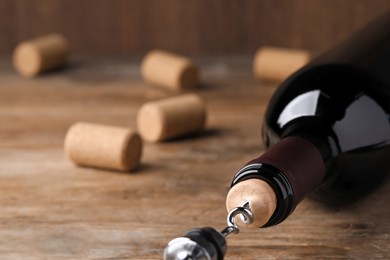 Opening wine bottle with corkscrew on wooden table, closeup. Space for text