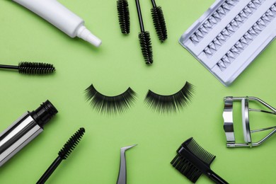 Photo of Flat lay composition with fake eyelashes, brushes and tool on green background