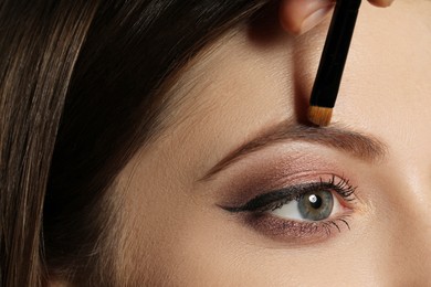 Photo of Artist correcting woman's eyebrow shape with powder, closeup