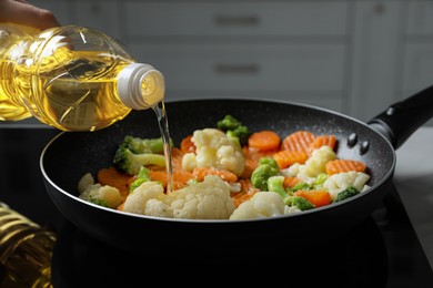 Photo of Woman pouring cooking oil from bottle into frying pan with vegetables, closeup