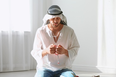 Muslim man in traditional clothes praying indoors