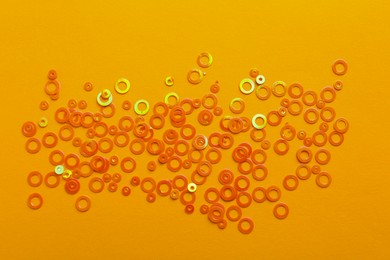 Photo of Shiny bright glitter on pale orange background, top view
