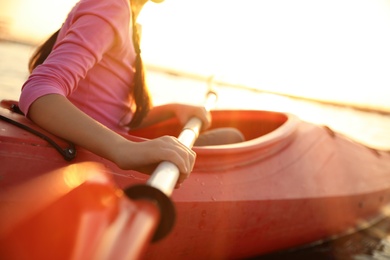 Little girl kayaking on river at sunset, closeup. Summer camp activity