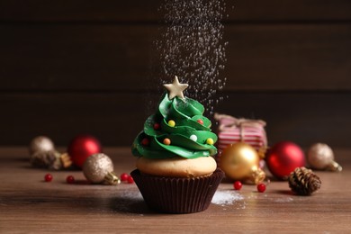 Photo of Sprinkling powdered sugar on Christmas tree shaped cupcake