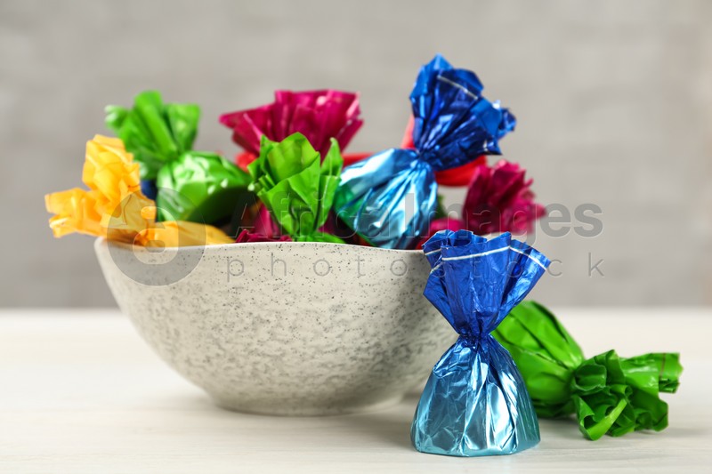 Candies in colorful wrappers on white wooden table, closeup