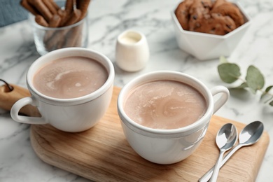Cups with hot cocoa drink on table