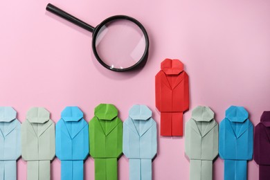 Photo of Many colorful paper figures and magnifying glass on pink background, flat lay. Recruiter searching employee