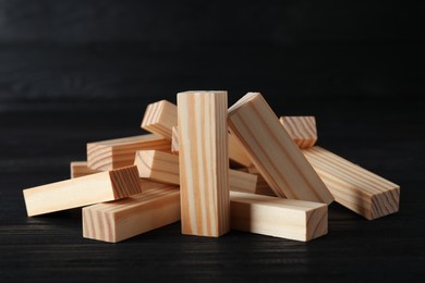 Pile of wooden blocks on black table. Jenga tower