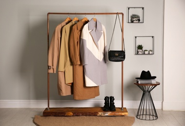 Different warm coats on rack in stylish room interior
