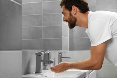 Handsome man washing hands in stylish bathroom