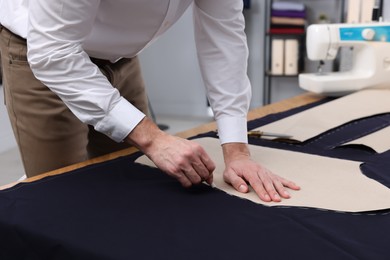 Photo of Dressmaker marking fabric with chalk in workshop, closeup