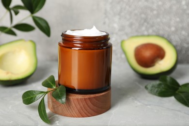 Photo of Jar of face cream and avocado on marble table