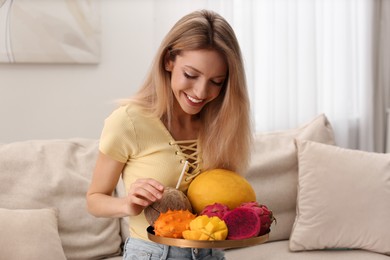 Photo of Young woman with fresh exotic fruits at home