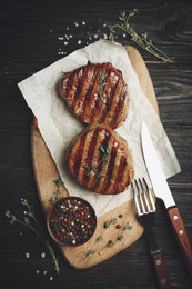 Delicious beef medallions served on black wooden table, flat lay. Food photography  