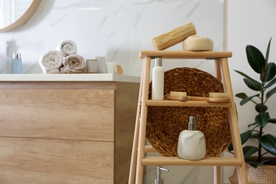 Photo of Dispensers and different toiletries on decorative ladder in bathroom. Idea for interior design
