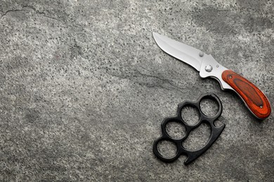 Brass knuckles and knife on grey background, flat lay. Space for text