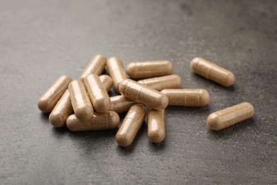 Dietary supplement capsules on grey table, closeup