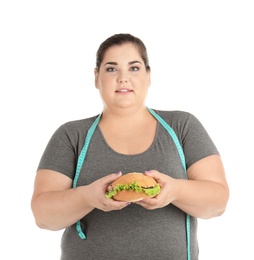 Overweight woman with hamburger and measuring tape on white background