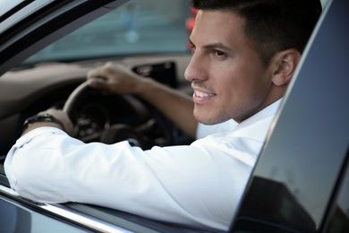 Handsome man in his modern car, view from outside