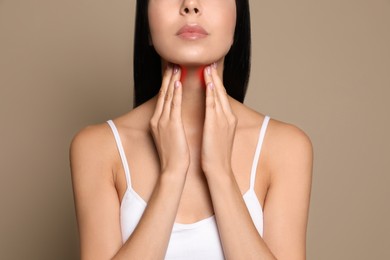 Image of Young woman doing thyroid self examination on beige background, closeup