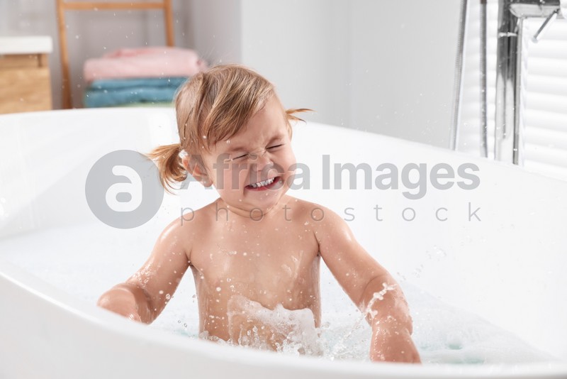 Photo of Cute little girl playing in bathtub at home