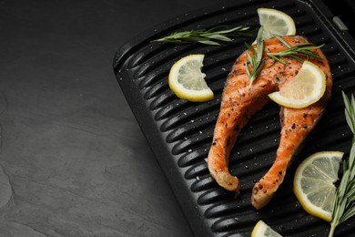 Cooking salmon. Grill with tasty fish steak, lemon and rosemary on grey table. Space for text