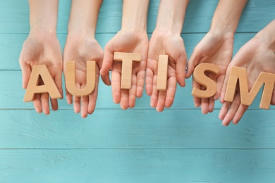 Group of people holding word "Autism" on wooden background