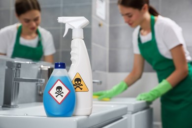 Bottle and spray of toxic household chemical with warning signs in bathroom