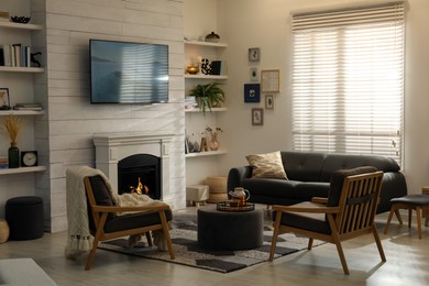 Cozy living room interior with comfortable sofa, armchairs and decorative fireplace