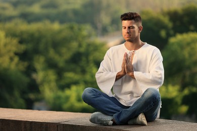 Man meditating outdoors on summer day. Space for text