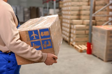 Image of Worker with cardboard box with shipping icons in warehouse, closeup. Wholesaling