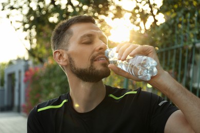 Man drinking water outdoors on hot summer day. Refreshing drink