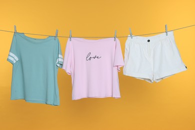 Photo of Different clothes drying on laundry line against orange background