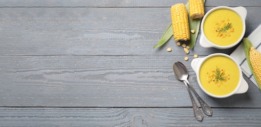 Delicious creamy corn soup served on grey wooden table, flat lay. Space for text
