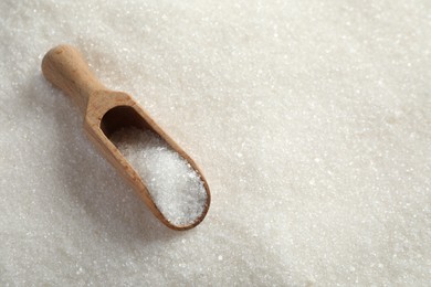 Photo of Granulated sugar and wooden scoop. Space for text