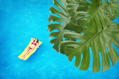 View of beautiful green monstera leaves and young woman on inflatable mattress in swimming pool, above view
