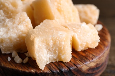 Pieces of delicious parmesan cheese on wooden board, closeup