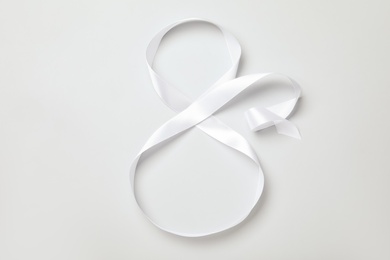 Number 8 made of white ribbon on light grey background, top view. International Women's day