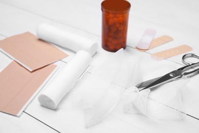 Photo of Bandage rolls and medical supplies on white wooden table, closeup
