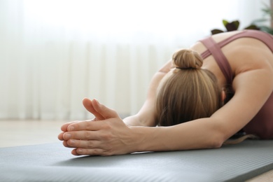 Young woman practicing extended child asana in yoga studio, focus on hands. Utthita Balasana pose